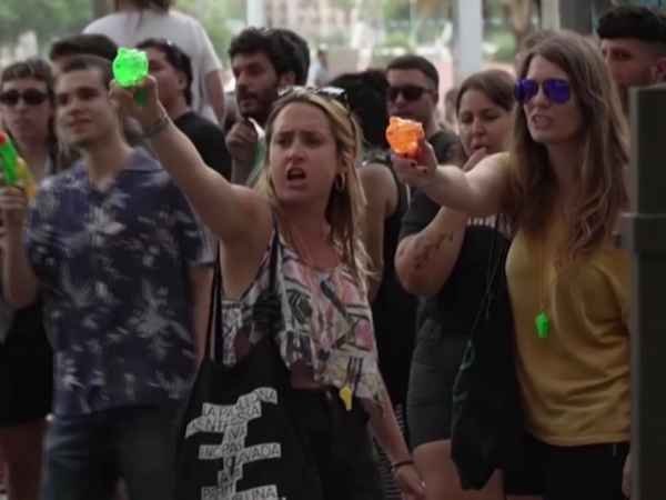 Mass tourism protesters in Barcelona, Spain, spray water at tourists