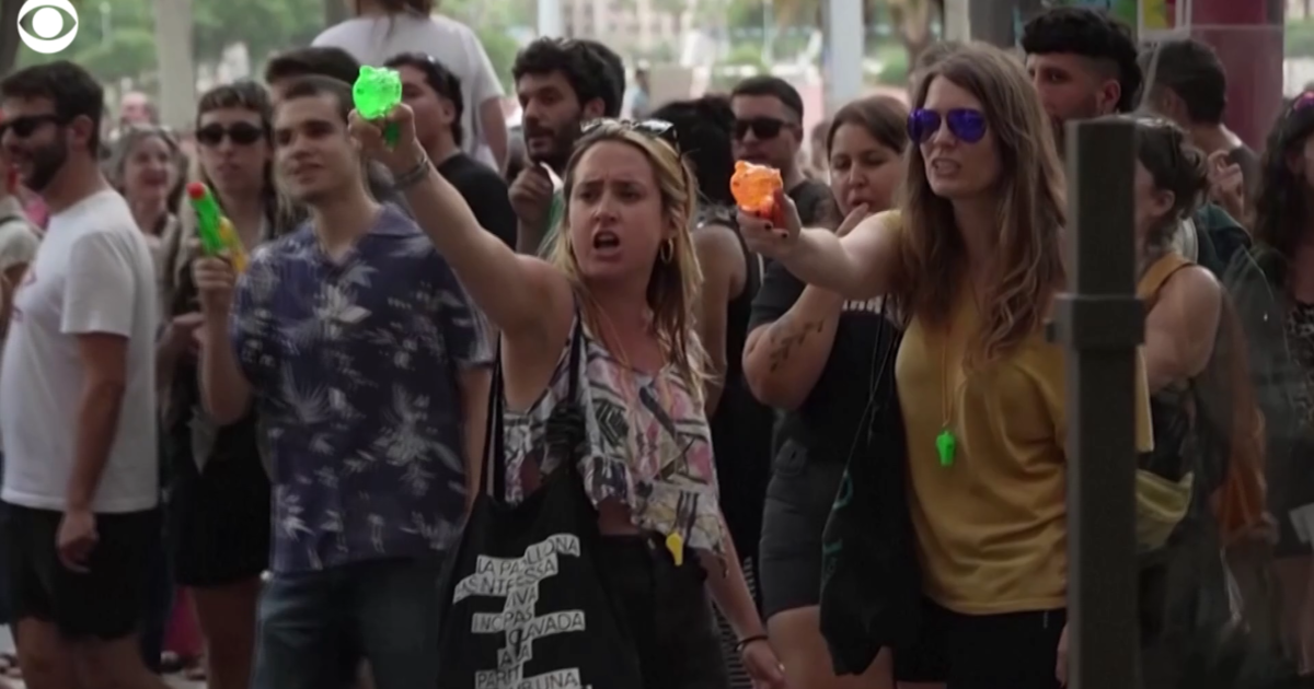 Mass tourism protesters in Barcelona, Spain, spray water at tourists